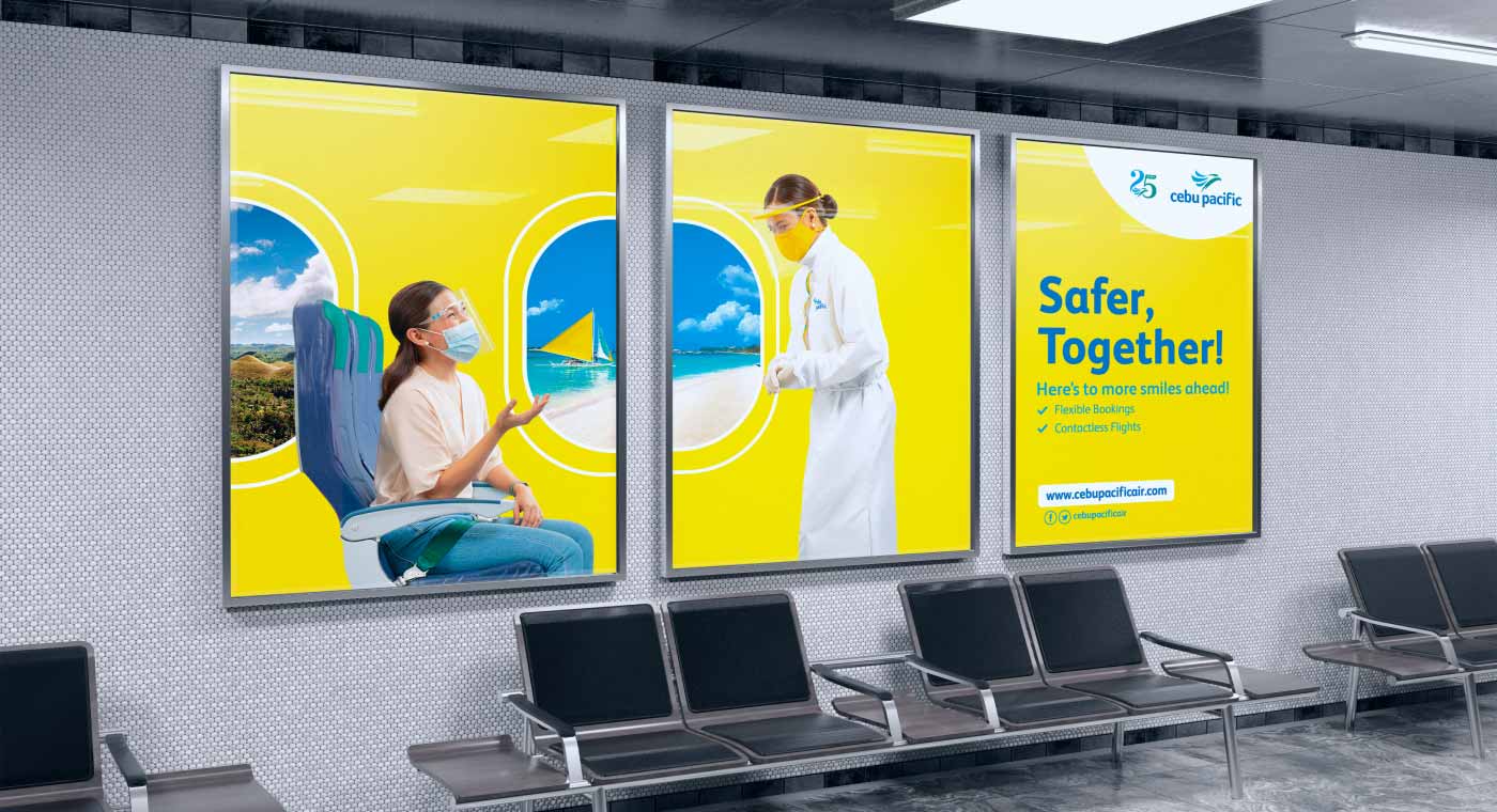 Light boxes inside the airport during COVID restrictions showing a Cebu Pacific passenger and flight attendant wearing masks and face shields. 